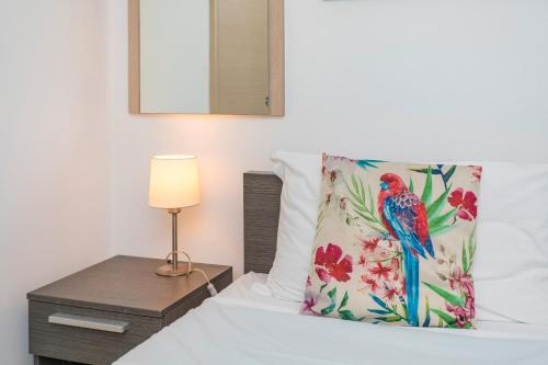 a bed with a colorful bird pillow and a night stand at Sirina Tao Beach in Taormina