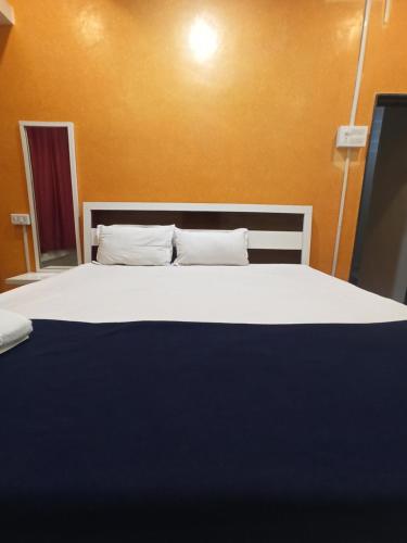 a bedroom with a large bed with white sheets and pillows at Malwade Motel in Pune