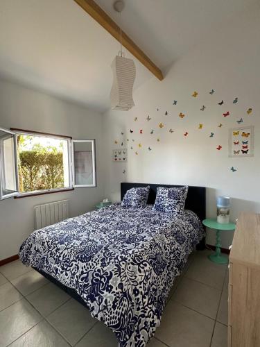 a bedroom with a bed with a blue and white comforter at Villa Gainsbourg in Andernos-les-Bains