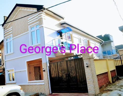 a white house with a sign that reads geniuses place at George's place service apartment in Sagisa