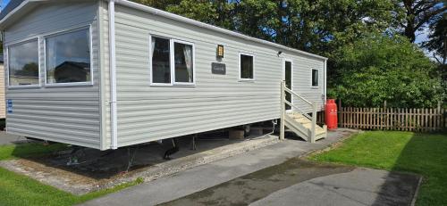 a white tiny house sitting in a yard at Lakeland leisure park sleeps up to 8 in Cark