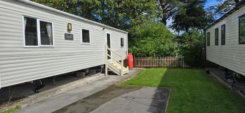 a white trailer with a yard next to a house at Lakeland leisure park sleeps up to 8 in Cark