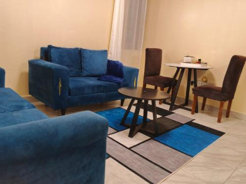 a living room with blue couches and a table at Luqman Apartments in Meru