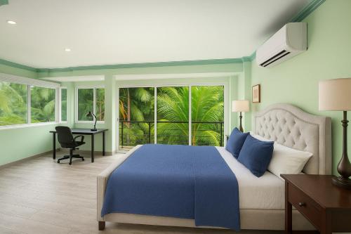 a bedroom with a blue bed and a desk and windows at P V near Colomitos Beach Boutique Hotel in Puerto Vallarta