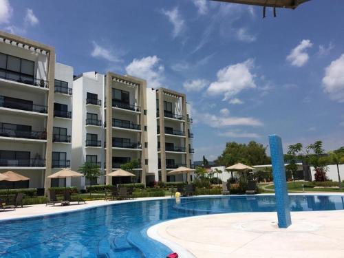 a swimming pool in front of a large apartment building at Depa within Paraiso Country Club Golf Club in Emiliano Zapata