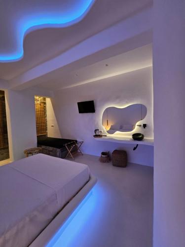 a white bedroom with a bed and a table at ELLI TROPiCAL LUXURY SUITES SUNSET-INFINITY POOL- SEA SIDE-NEAR CENTER PARKING in Mikonos