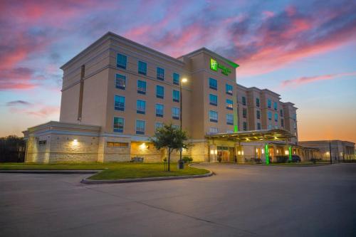 a hotel building with a green sign on top of it at Holiday Inn & Suites Houston NW - Willowbrook by IHG in Houston