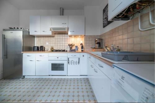 une cuisine avec des armoires blanches et un évier dans l'établissement LE DARCET - Hypercentre - Calme - Proche Gare & Thermes, à Vichy