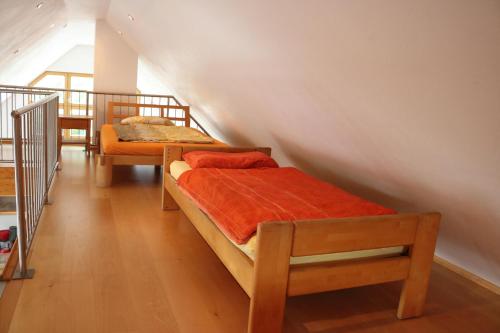 1 Schlafzimmer mit 2 Betten und orangefarbener Bettwäsche in der Unterkunft Apartment Dachgalerie in München