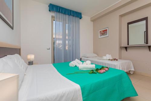 a hotel room with a bed with towels and flowers on it at Sirina Tao Beach in Taormina