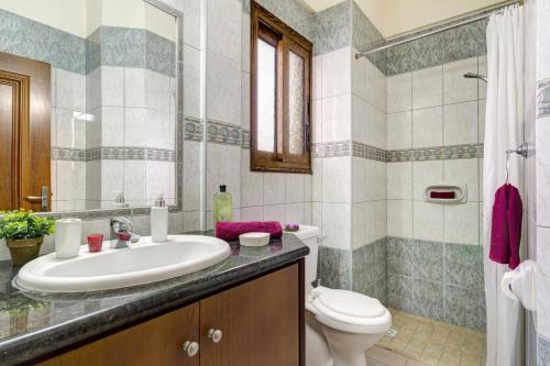 a bathroom with a sink and a toilet at Villa Antonia by Villa Plus in Peyia