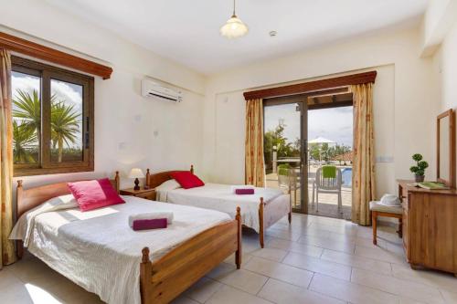 a bedroom with two beds and a balcony at Villa Antonia by Villa Plus in Peyia