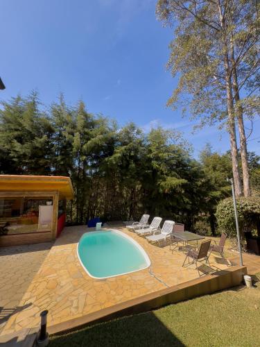 a swimming pool with lounge chairs and a table at Pousada das Acácias in Camanducaia