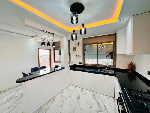 a kitchen with white cabinets and black counter tops at Happy Monkey Villa Taghazout in Aït Ahmed