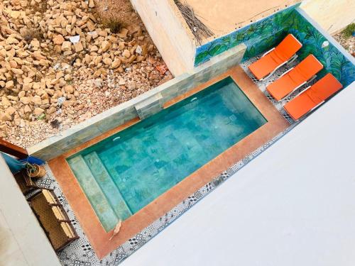 a swimming pool with orange chairs in it at Happy Monkey Villa Taghazout in Aït Ahmed