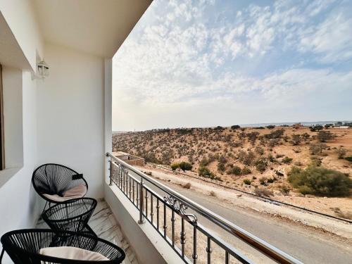 a balcony with two chairs and a view of the desert at Happy Monkey Villa Taghazout in Aït Ahmed