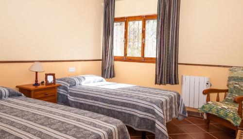 a room with two beds and a chair and a window at Cortijo La Molina de Cabo de Gata in El Cabo de Gata