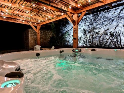 a jacuzzi tub under a pergola with lights at Gîte - Chez Gabriel et Julie in Viviers