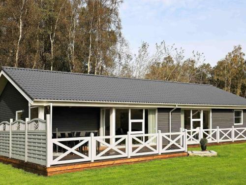 a small house with a white fence in the grass at 4 star holiday home in Væggerløse in Bøtø By