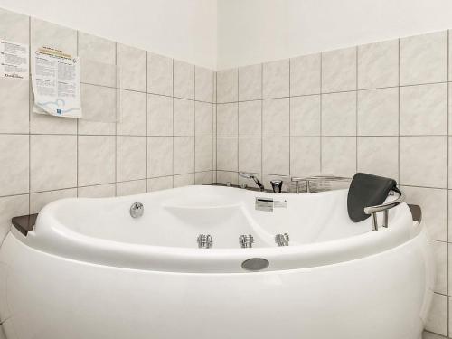 a white bath tub in a white tiled bathroom at 4 star holiday home in Væggerløse in Bøtø By