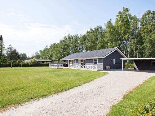 a house on a beach with a grass field at 4 star holiday home in Væggerløse in Bøtø By
