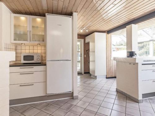 a kitchen with white cabinets and a refrigerator at Renovated Retreat near Beach - By Traum Ferienwohnungen in Blåvand