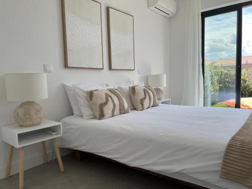 a white bedroom with a bed and a window at Casa Beliche in Aljezur