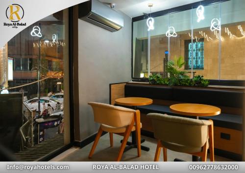 a restaurant with two tables and chairs in front of a window at Roya Downtown Boutique Hotel in Amman