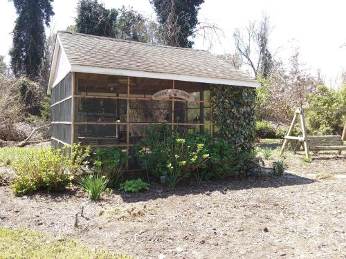 a small greenhouse in a garden with plants at Island House of Wanchese Bed and breakfast in Wanchese