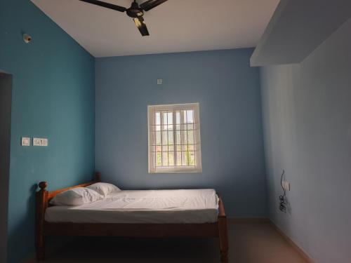 a blue room with a bed with a window at Yogi Bhagavan HOME STAY in Tiruvannāmalai