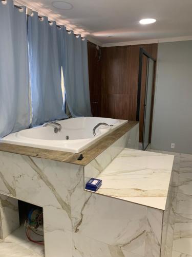 a bathroom with a tub and a marble counter at Pousada Mirante Da Guariba in Angra dos Reis