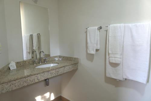 a bathroom with a sink and a mirror and towels at Itatiba Orion Hotel in Itatiba