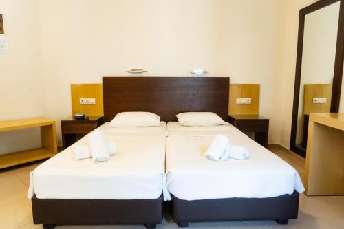 two beds in a hotel room with white sheets at Your Memories Hotel in Gouves