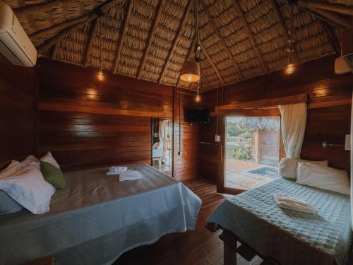 a bedroom with two beds in a wooden room at Pacas Suítes Lençóis Eco Lodge in Santo Amaro