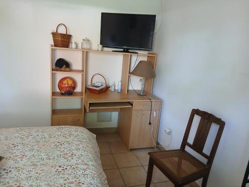 a bedroom with a desk with a television and a chair at une Chambre meublé chez habitant in Roézé-sur-Sarthe