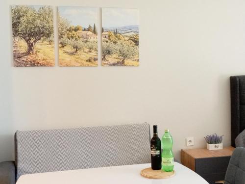 three paintings on a wall above a table with two bottles at Batumi View COMFORT in Batumi