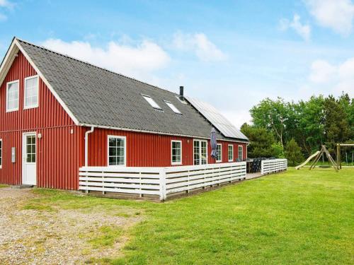 a red barn with a white fence and a playground at Luxury Retreat with Pool - By Traum Ferienwohnungen in Toftum