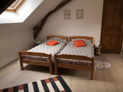 2 letti con cuscini arancioni in una camera da letto di Appartement à l'Aujardière a Durtal