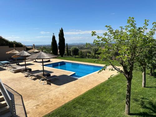 a pool with chairs and umbrellas in a yard at Can Gala - Appartment & Private Pool in Pau