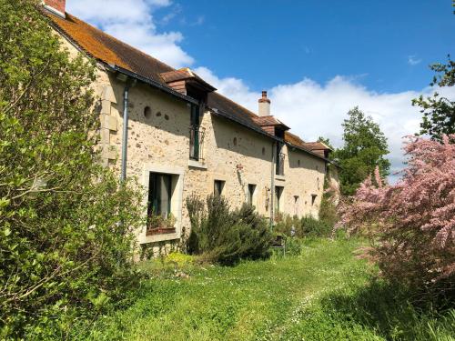 una vecchia casa in pietra con un giardino antistante di Chambres Au Calme, À La Campagne a Durtal