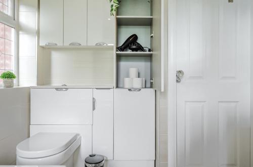 a white bathroom with a toilet and a door at Hilton House - stylish 4-bed with parking in Manchester
