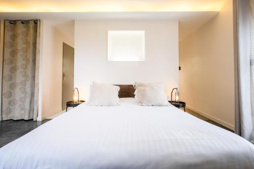 a bedroom with a large white bed with two pillows at A l'Ombre d'Azay - Demeure d'Hôtes - GuestHouse in Azay-le-Rideau