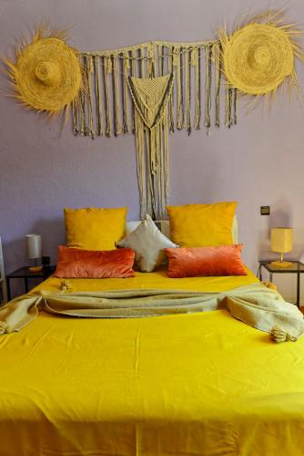 a large bed with yellow sheets and orange pillows at Riad Parfums de OUARZAZATE in Ouarzazate