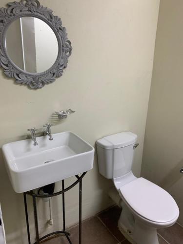 a bathroom with a toilet and a sink and a mirror at Sunset Guesthouse and Venue Cullinan in Meule