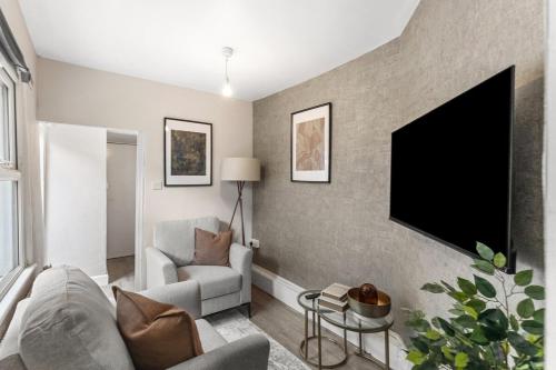 a living room with a couch and a tv on a wall at Cosy Gem & Garden Fast access to Central London in London