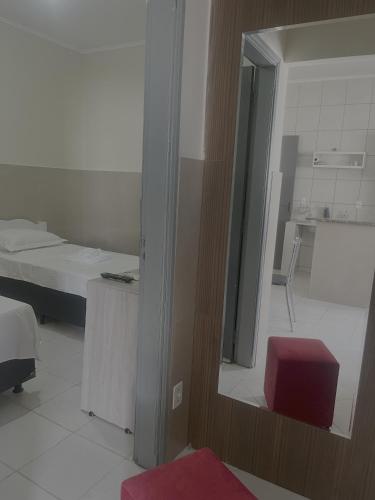 a mirror in a room with a bed and a red stool at Casa Progresso em Anápolis in Anápolis