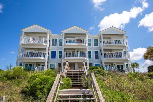 a large white building on the beach with stairs at Whispering Sands 1A in Coffeyville