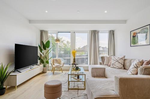 a living room with a couch and a tv at Luxury Apartment - West Wimbledon with Cinema & Game Room, Gym, Parking in New Malden