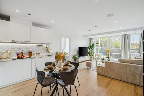 a kitchen and living room with a table and chairs at Luxury Apartment - West Wimbledon with Cinema & Game Room, Gym, Parking in New Malden