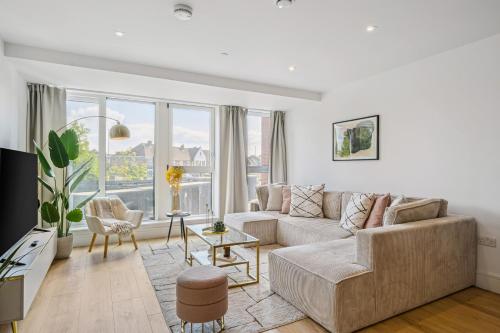 a living room with a couch and a large window at Luxury Apartment - West Wimbledon with Cinema & Game Room, Gym, Parking in New Malden
